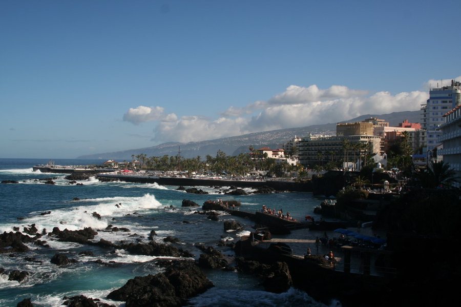 Hotel su una costa rocciosa con onde e passeggiata